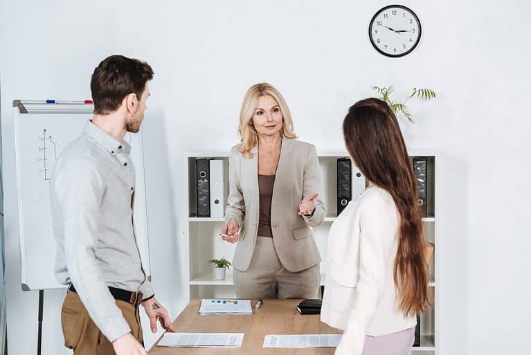 professional mature businesswoman standing and talking with young colleagues in office