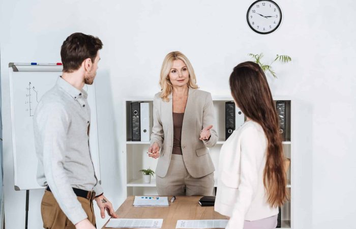 professional mature businesswoman standing and talking with young colleagues in office
